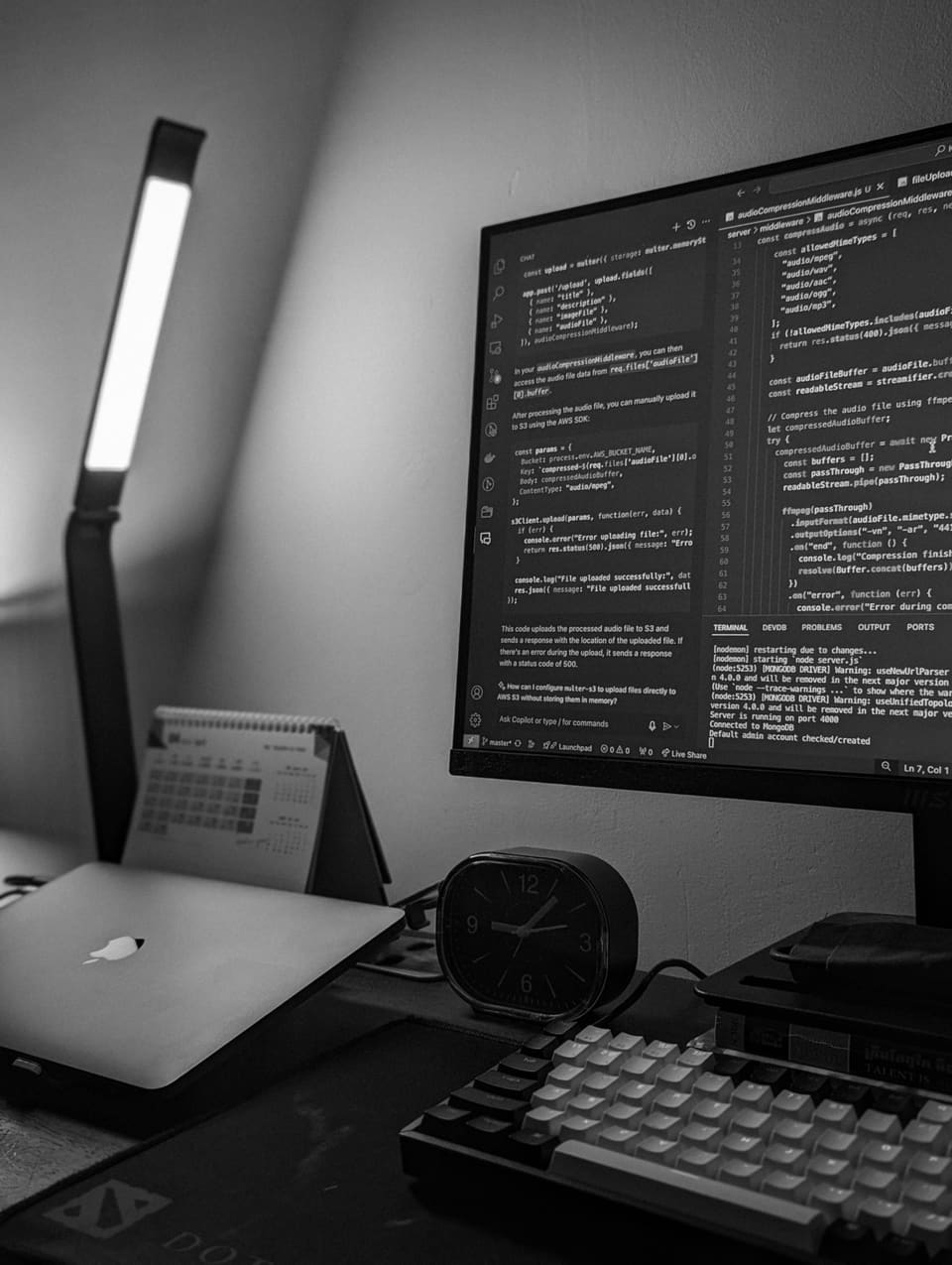Schwarz-Weiß-Aufnahme eines Entwickler-Arbeitsplatzes mit Monitor und Code-Editor